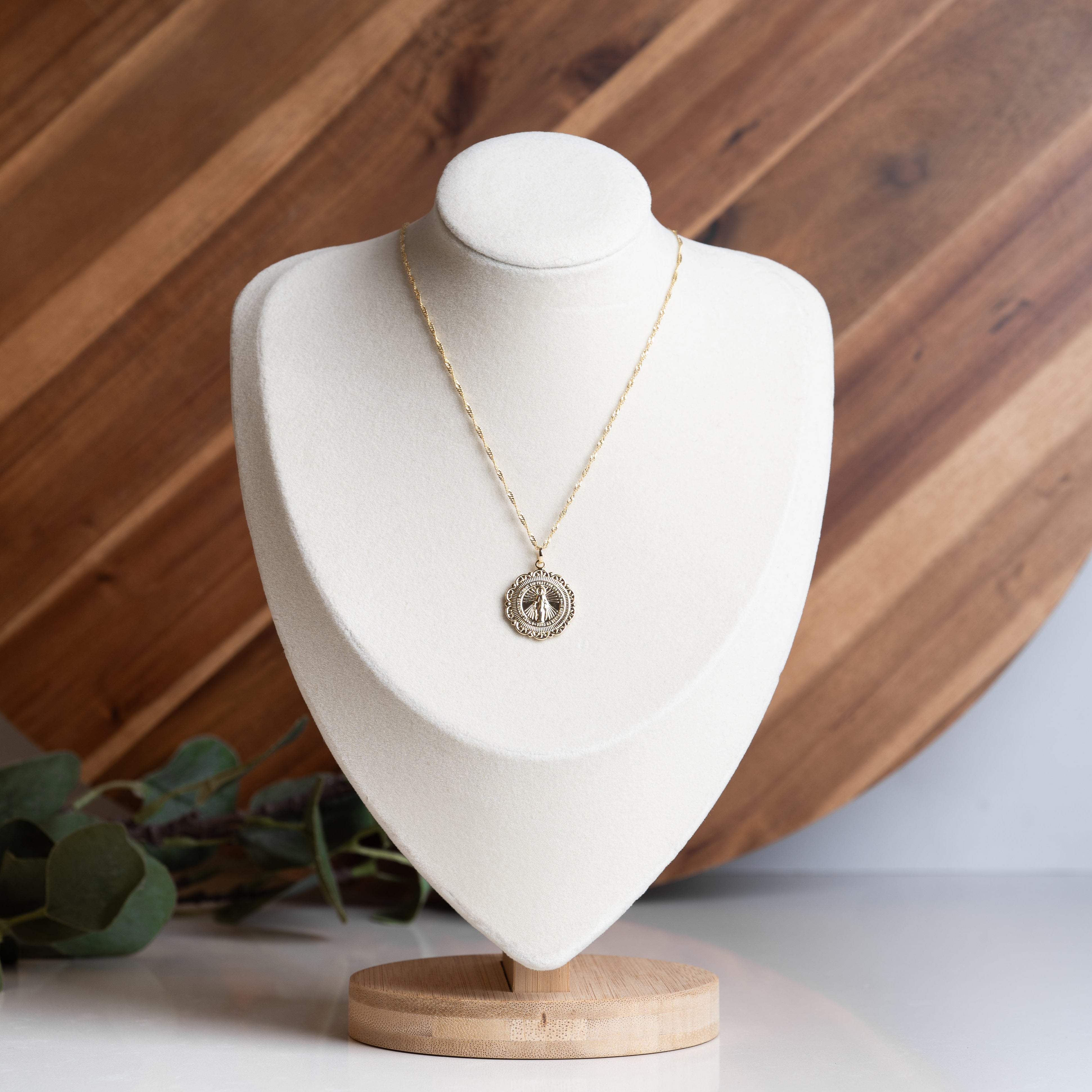 Miraculous Medal Necklace on a white holder with a wooden background